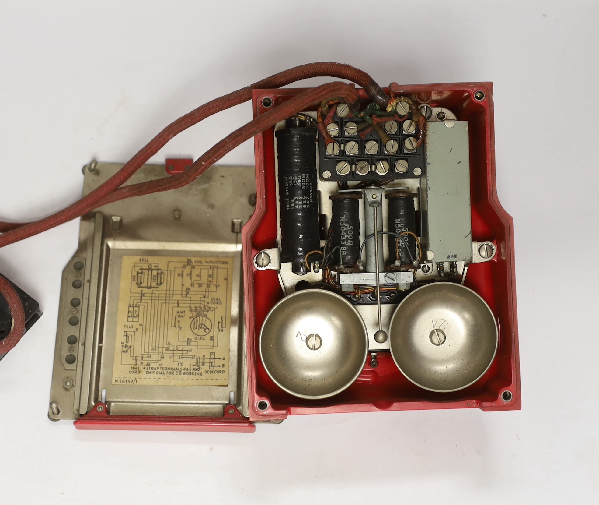 A red 1950s Ericsson Telephones Ltd telephone made in the pattern of a GPO 332 series bakelite telephone, serial no.N1002A 23T, understood to be intended for issue in a tropical country